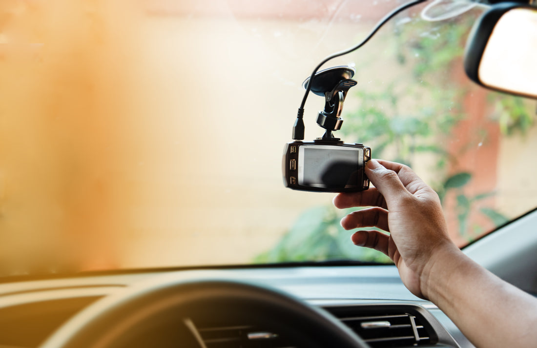 Driver reaching up to check a dash cam mounted on the windscreen — dash cam troubleshooting guide for Australia